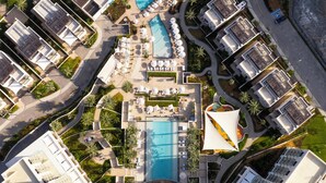 Ein Luftbild eines Resorts mit mehreren Swimmingpools, Liegestühlen und Palmen.