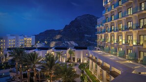 Ein modernes Hotel mit mehreren Etagen, Balkonen und Blick auf eine gebirgige Landschaft.