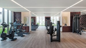 A modern gym with cardio equipment, weight machines, and a large mirror. - Address Beach Resort Fujairah (Al Aqah)