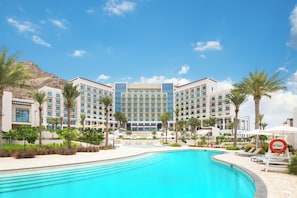 Un hôtel doté d’une piscine, de palmiers et surplombant un paysage montagneux.