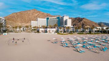 A beach with a volleyball court, umbrellas, and beach chairs.