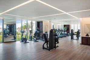 Una palestra moderna con diverse attrezzature per l'allenamento, ampie finestre e un pavimento in legno.