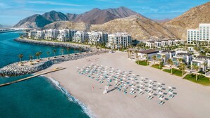 Ein Hotel an der Küste mit mehreren Gebäuden, einem Sandstrand und einer felsigen Uferlinie.