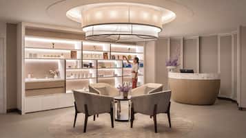 A modern reception area with a central chandelier, a reception desk, and a seating area with chairs and a table.
