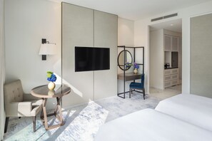 Een moderne hotelkamer met een bed, een bureau met stoel, een televisie, een spiegel en een klein tafeltje met vaas.