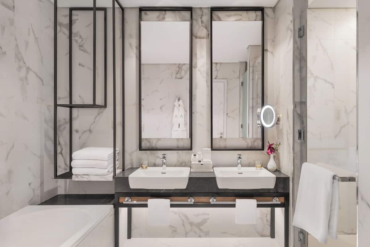 Un baño moderno con dos lavamanos, un espejo grande y una bañera.