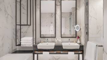 Une salle de bain moderne avec deux lavabos, un grand miroir et une baignoire.