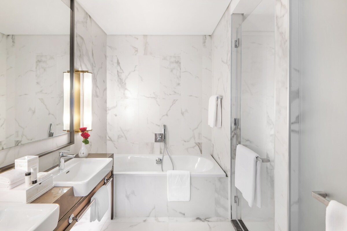 Une salle de bain moderne avec un grand miroir, deux lavabos, une baignoire et une douche.