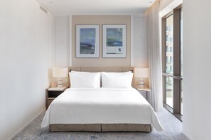 A hotel room with a large bed, two bedside tables, a nightstand, a window with a view, and two framed artworks on the wall. - Address Beach Resort Fujairah (Al Aqah)