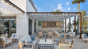 An outdoor patio with seating arrangements, a central table, and a kitchen area visible through the glass doors. - Address Beach Resort Fujairah (Al Aqah)