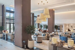 Un'ampia hall con diverse zone relax, ampie finestre e lampade dal design moderno.