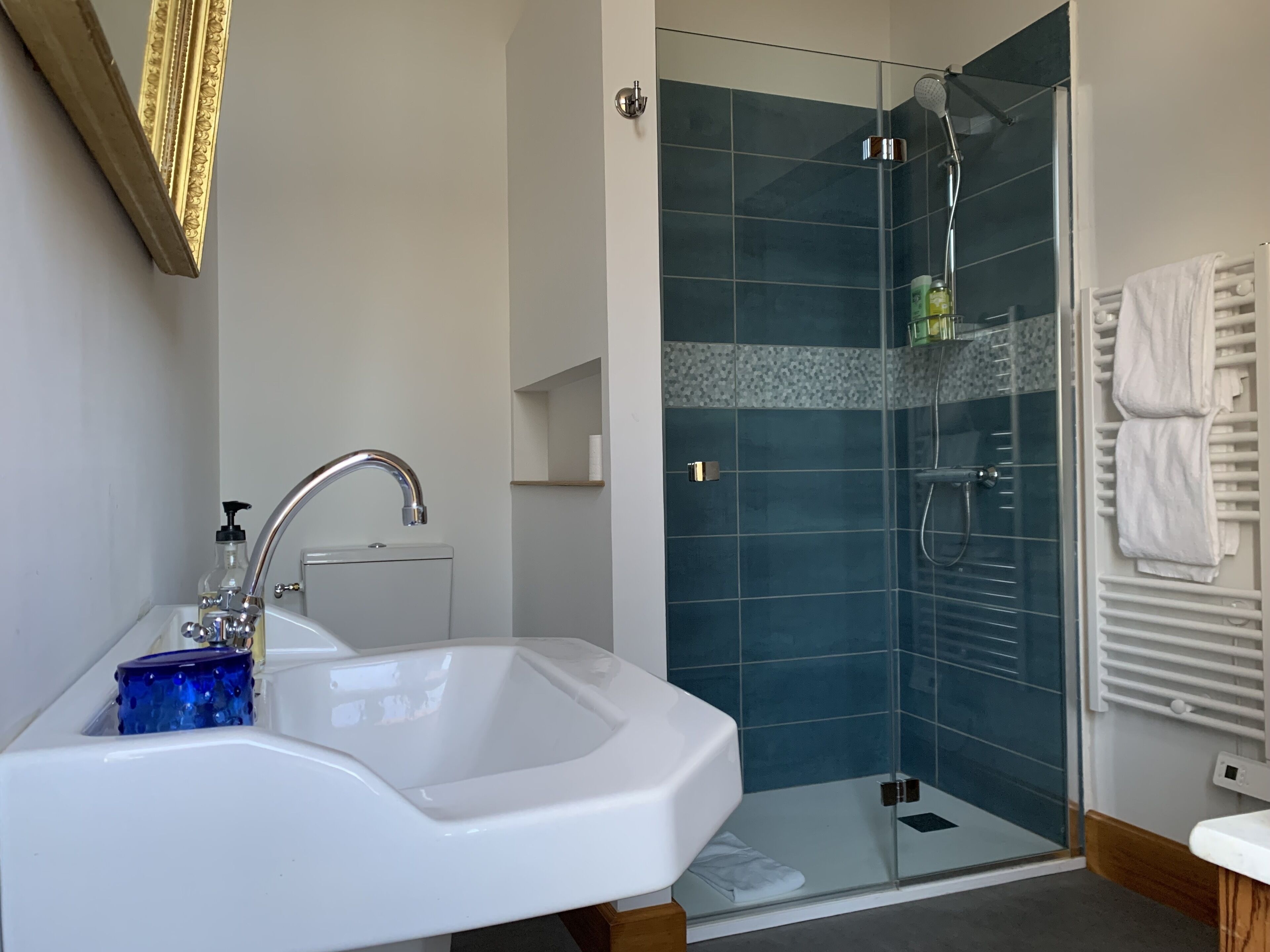 A modern bathroom with a white sink, a glass shower enclosure, and a towel rack.
