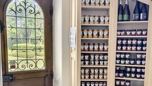 A wooden door with a decorative glass window, a tiled entrance, and shelves stocked with jars and bottles. - L'abeaupinière (Reboursin)