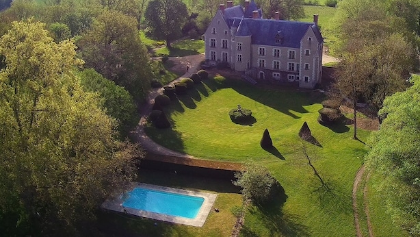 An aerial view of a large, historic mansion with a well-manicured lawn, a swimming pool, and a surrounding landscape. - L'abeaupinière (Reboursin)