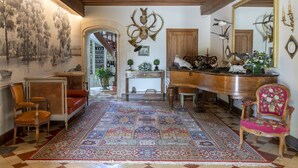 A room with a large ornate mirror, a grand piano, and a red upholstered chair. - L'abeaupinière (Reboursin)
