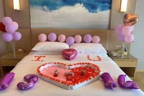 A hotel room with a bed adorned with a heart-shaped arrangement of rose petals, balloons, and a 'I ♥ U' sign. - Vienna International Hotel (Dongguan Hongmei Town) (Dongguan)
