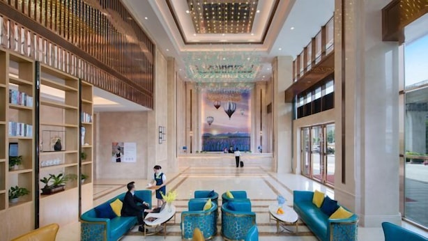 A spacious lobby with a central seating area, a reception desk, and a mural on the back wall. - Vienna International Hotel (Dongguan Hongmei Town) (Dongguan)