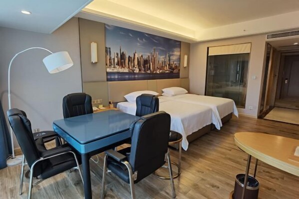 A hotel room with a bed, a desk with chairs, a lamp, and a painting of a cityscape on the wall. - Vienna International Hotel (Dongguan Hongmei Town) (Dongguan)