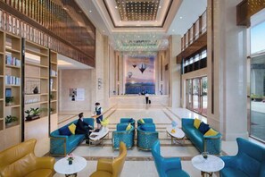 A spacious lobby with seating areas, a reception desk, and a large mural on the wall. - Vienna International Hotel (Dongguan Hongmei Town) (Dongguan)