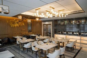 A restaurant with multiple tables and chairs, a bar area, and a modern interior design. - Vienna International Hotel (Dongguan Hongmei Town) (Dongguan)