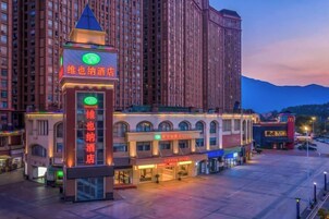 Un hotel con una torre destacada, varios edificios a nivel de calle y un estacionamiento.