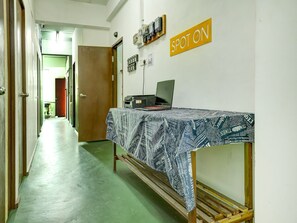 Käytävällä on sänky, kannettava tietokone ja kyltti, jossa lukee: ”TÄSMÄLLINEN”.