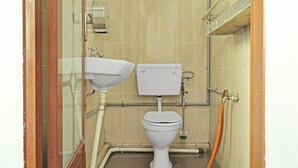 Une petite salle de bain compacte comprenant des toilettes, un lavabo et un espace douche.