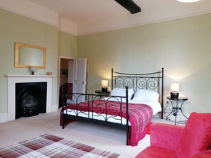 A bedroom with a four-poster bed, a fireplace, a mirror, and two bedside lamps.