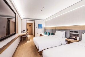 Een hotelkamer met twee bedden, een bureau, een stoel, een tafeltje en een tv aan de muur.