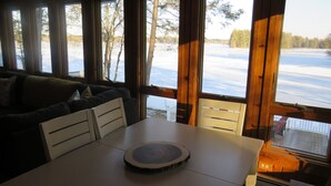 A cozy cabin interior with a wooden table, a white chair, and a sofa. - Charming and spacious lakefront home with 4 bedrooms, hot tub and pool table! (Farmington)
