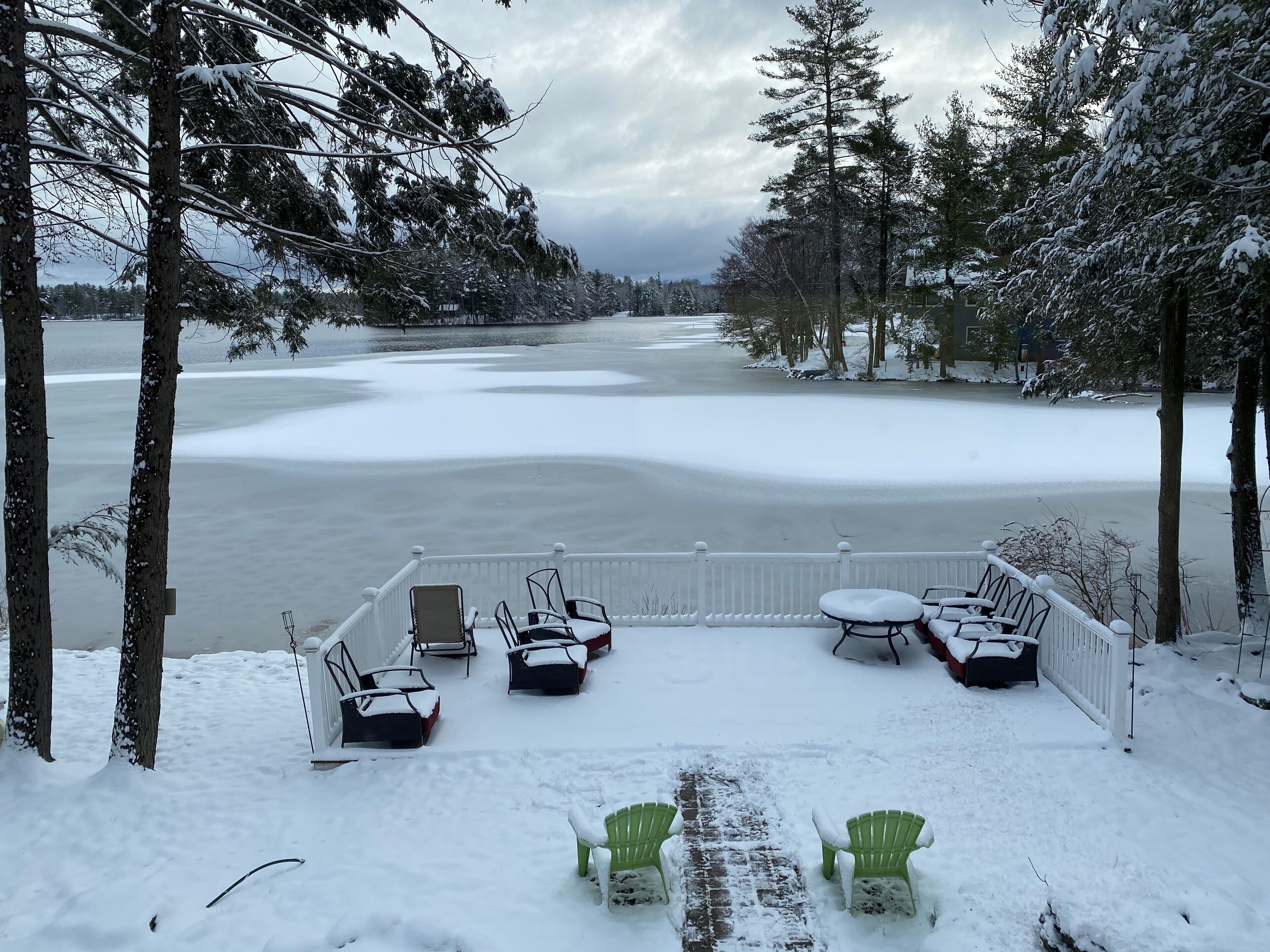 A snow-covered deck with outdoor seating and a view of a frozen lake.