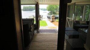 A view from a covered porch to a lake with a grill and outdoor furniture. - Charming and spacious lakefront home with 4 bedrooms, hot tub and pool table! (Farmington)