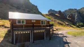 A two-story house with a metal roof, a wooden deck, and a garage.