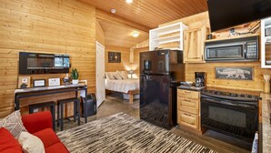 A cozy log cabin interior with a kitchen, dining area, and a bed.