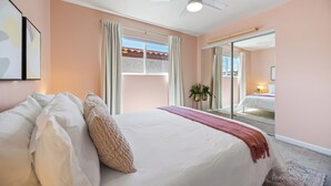 Ein Schlafzimmer mit einem großen Bett, einem Deckenventilator und einer Glastür, die auf einen Balkon führt.