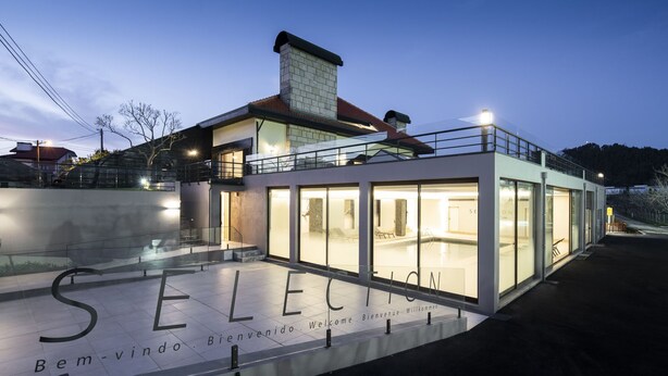 A modern hotel with a glass facade, a visible pool area, and a welcoming entrance with "Bienvenue" signage.