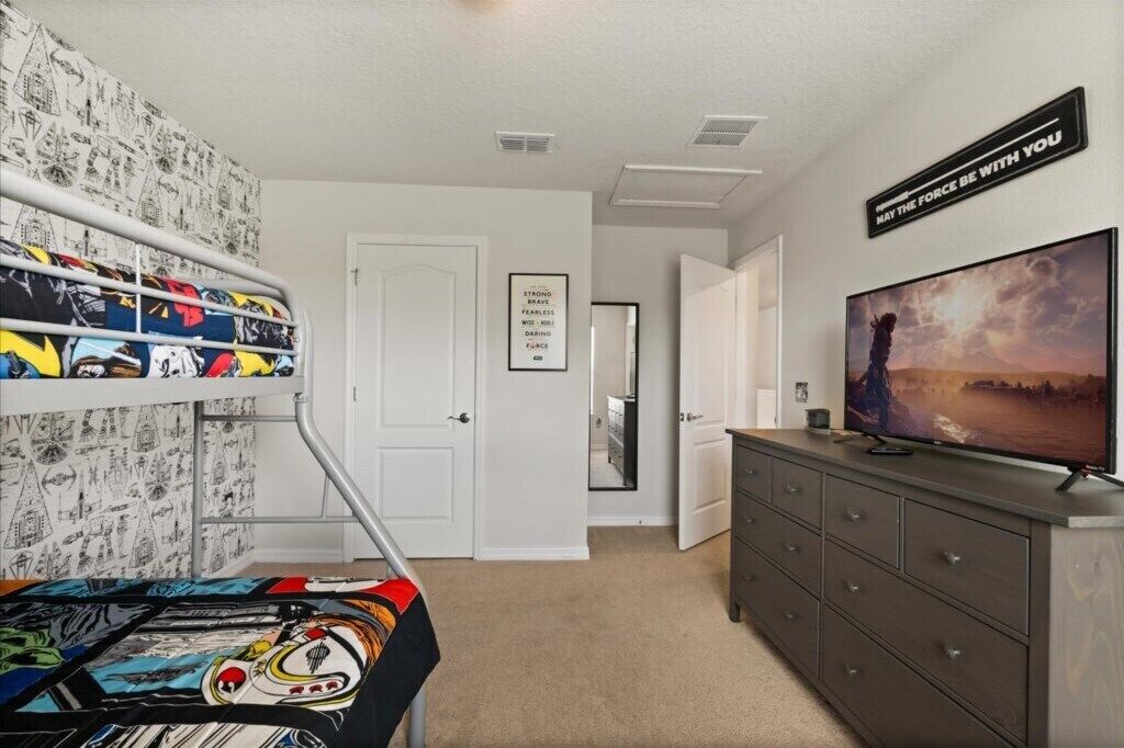 A room with a bunk bed, a dresser, a television, and a motivational poster.