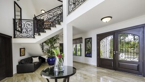 A spacious living area with a black leather sofa, a glass table with a vase, and a staircase with ornate black railings. - Amazing Private Villa with Chef & Maids (Punta Cana)