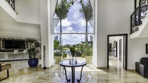 A spacious lobby with a large glass window, a round table, and a potted plant. - Amazing Private Villa with Chef & Maids (Punta Cana)