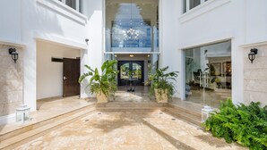A modern building with a glass entrance, potted plants, and a marble floor. - Amazing Private Villa with Chef & Maids (Punta Cana)
