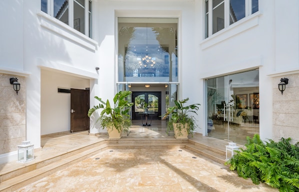 A modern building with a glass entrance, potted plants, and a marble floor.