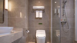 Un baño moderno con cabina de ducha de vidrio, inodoro blanco y un lavabo grande.
