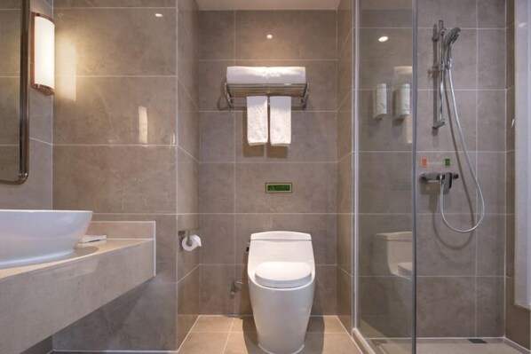 Un baño moderno con cabina de ducha de vidrio, inodoro blanco y un lavabo grande.