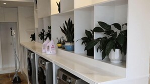Una cocina con electrodomésticos integrados, una encimera con plantas en macetas y un área de lavandería.
