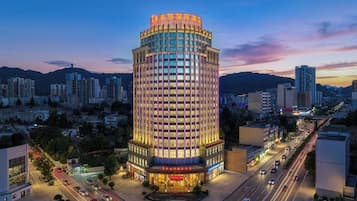 A multi-story hotel with a prominent corner location, surrounded by a busy urban street and other buildings.
