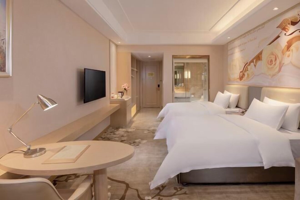 Habitación de hotel con cama, escritorio, silla, televisión y un gran mural en la pared.