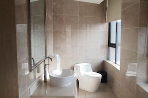Un baño moderno con un espejo grande, un lavamanos sobre encimera, un inodoro y una ventana que proporciona luz natural.