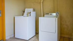 Two white front-loading washing machines in a laundry room with tiled flooring and a beige wall.
