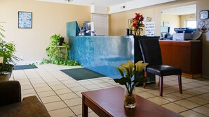 A reception area with a counter, chairs, a desk, and a plant.
