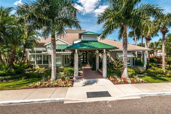Stunning two-story building with a covered entrance, surrounded by lush greenery and large windows.